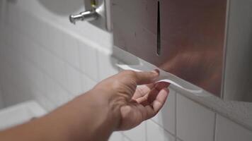 Hand reaches for paper towel in public restroom setting video