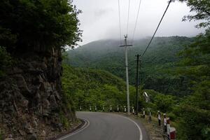 Turn of the road with incredible view of mountains and forest in fog, cloudy photo