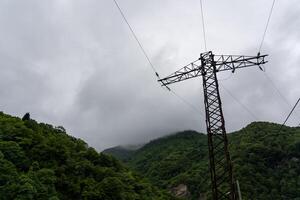 Support of power lines against the background of mountains and thick clouds photo