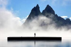 A person standing on a dock in front of a mountain photo