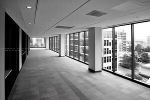 A black and white photo of a long hallway with large windows
