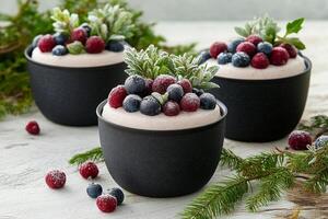 Three cups of pudding with berries and sprigs of fir photo