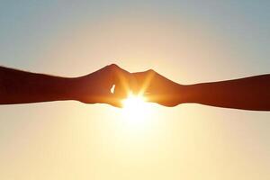 Two hands holding each other in front of the sun photo
