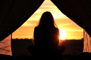 A woman sitting in a tent at sunset photo