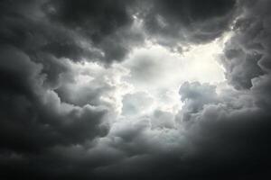 A dark cloud filled sky with a sun shining through photo