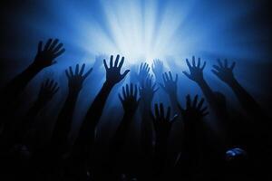 Hands reaching up in the air at a concert photo