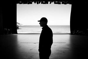 A man standing in front of a stage looking out at the ocean photo