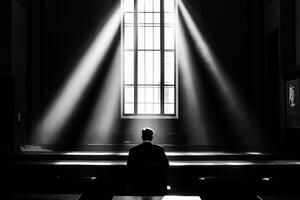 A man sits in a dark room with light shining through the window photo
