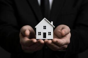 A man in a suit holding a house model photo