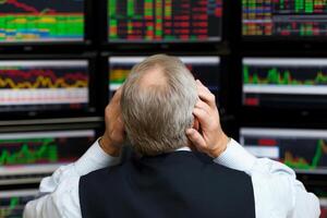 A man is looking at multiple screens of stock market data photo