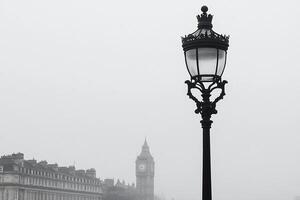 A street lamp in the fog with a clock tower in the background photo