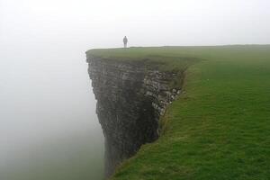 A person standing on top of a cliff in the fog photo
