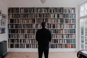 Man standing in front of a large bookcase photo