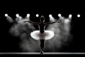 A ballerina in a white tutu and skirt is standing in front of a spotlight photo