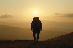 A person with a backpack standing on top of a mountain at sunset photo