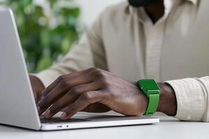 A man wearing a green wristband on his wrist while using a laptop photo