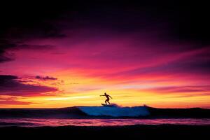 A person riding a wave on a surfboard at sunset photo