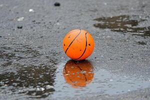 A basketball ball is sitting in a puddle of water photo