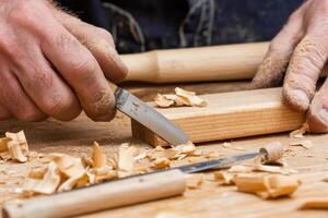 A man is using a woodworking tool to make a piece of wood photo