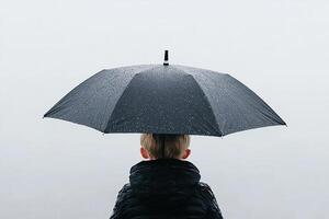 A child standing under an umbrella in the rain photo