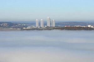 A city is seen in the fog on a hill photo