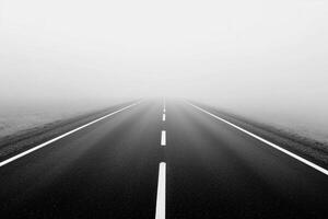 Black and white photo of empty road in fog