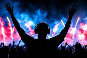 A person with headphones and arms up in front of a crowd photo