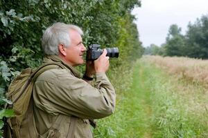 A man with a camera taking a photo of a field