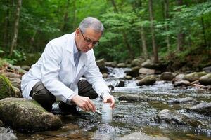 A man in a lab coat is kneeling down in a stream photo