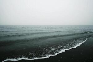 A black and white photo of a beach with waves