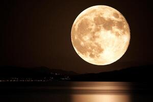 The moon is reflected in the water as it rises over the mountains photo