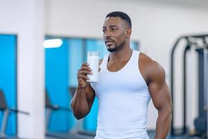 A man is holding a bottle of water in a gym photo