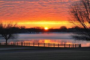 A beautiful sunset over a lake with a fence photo