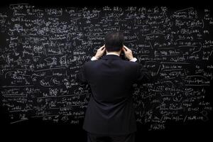 A man in a suit standing in front of a blackboard with formulas written on it photo