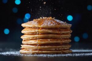 Stack of pancakes with syrup and sugar on a dark background photo
