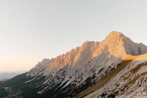 A mountain range in the sun with a person standing on top photo
