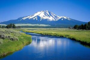 A mountain with a river and grassy field photo