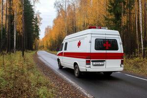 A white and red ambulance driving down a road photo