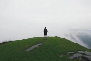 A person standing on top of a hill looking at the clouds photo