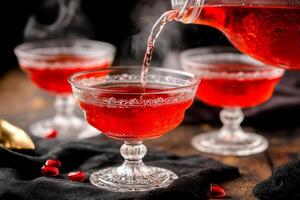 Pouring red liquid into glasses with red garnish photo