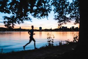 A person running along the shore at sunset photo