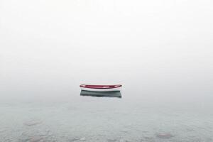 A red boat floating in the fog on a lake photo