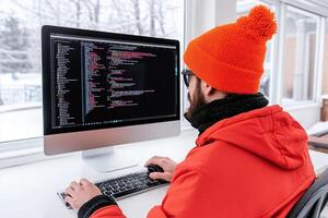 A man wearing an orange hat is working on a computer photo
