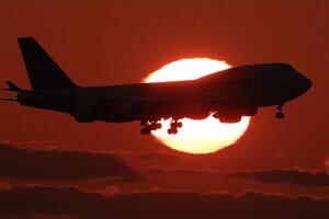A large airplane flying in the sky at sunset photo