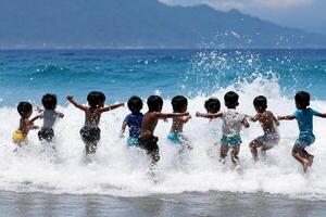 A group of kids playing in the ocean photo