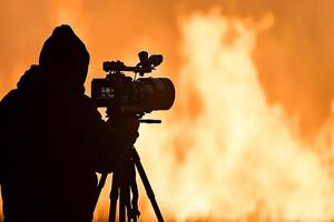 A man is holding a camera in front of a fire photo