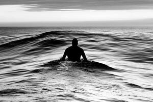 A man is standing in the middle of the ocean photo