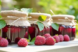 Three jars of raspberry jam with berries on a wooden table photo