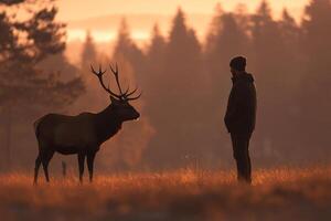 A man standing in front of a deer in a field photo