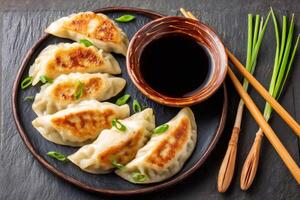 Fried gyoza dumplings with soy sauce and chopsticks on dark background photo